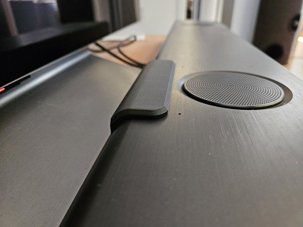 A sleek black cover over the controls of a soundbar